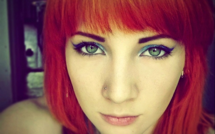 Close-up of a young woman with red hair and blue eyeliner