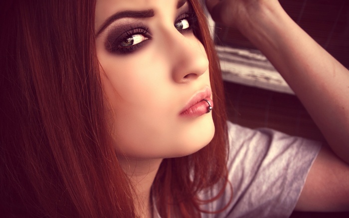 Redhead woman with pierced lips and smoky eye makeup