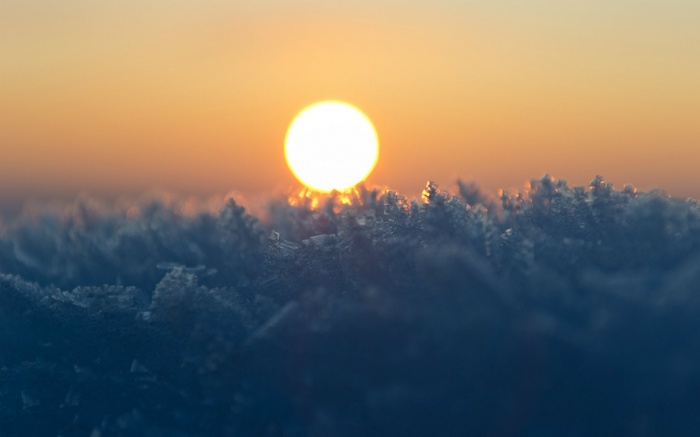 Sun setting over frost-covered ground