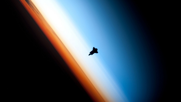 Space Shuttle silhouetted against Earth's atmosphere