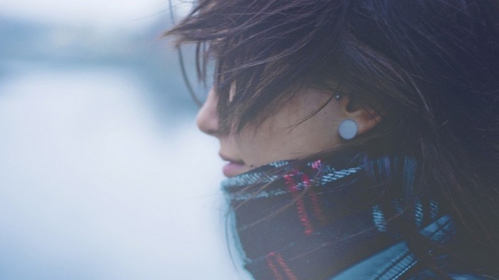 Woman with hair in face wearing a scarf
