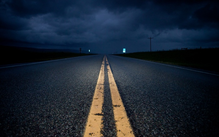 Empty road at night under dark clouds