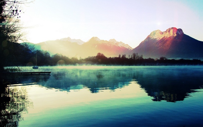 Boat on a misty lake with mountains in the background