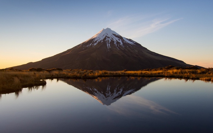 Mount Taranaki reflected in a lake at sunrise