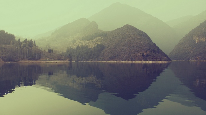 Misty mountains reflected in a calm lake