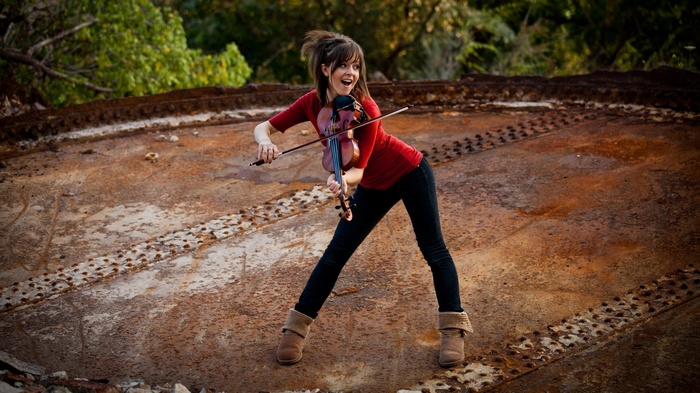 Lindsey Stirling plays the violin on a rusty surface