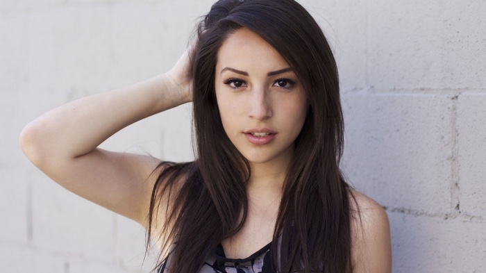 Chloe Gueit with long dark hair and a brick wall