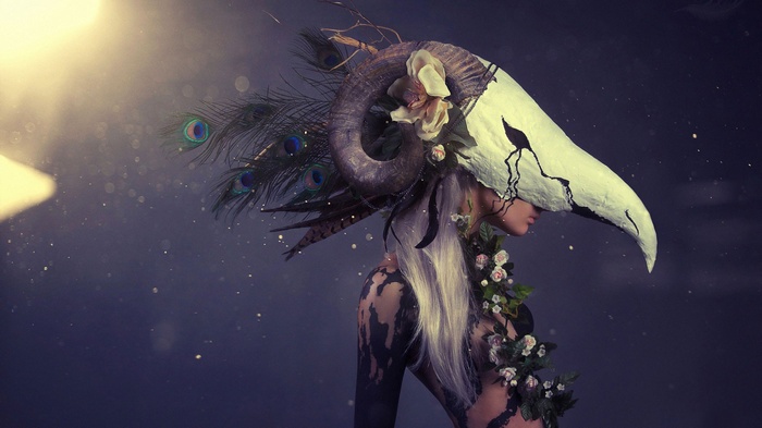 Woman with ram skull and peacock feathers headdress
