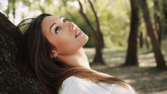 Woman leaning against a tree in a park