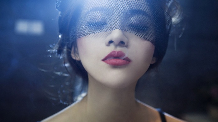 Woman wearing a black veil and red lipstick smoking