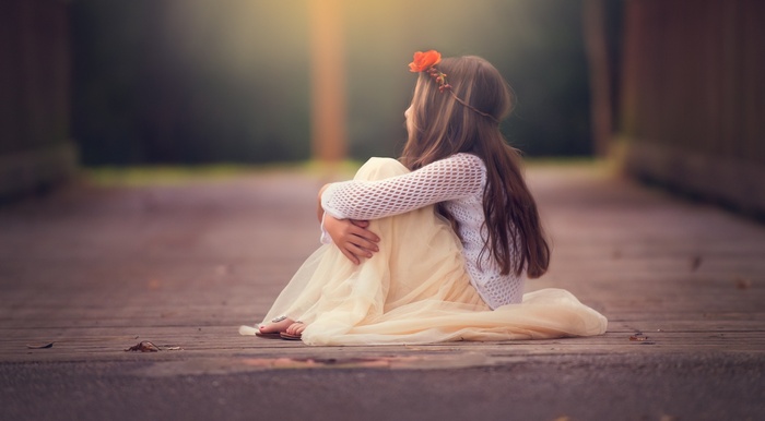 A young girl sitting on a wooden path