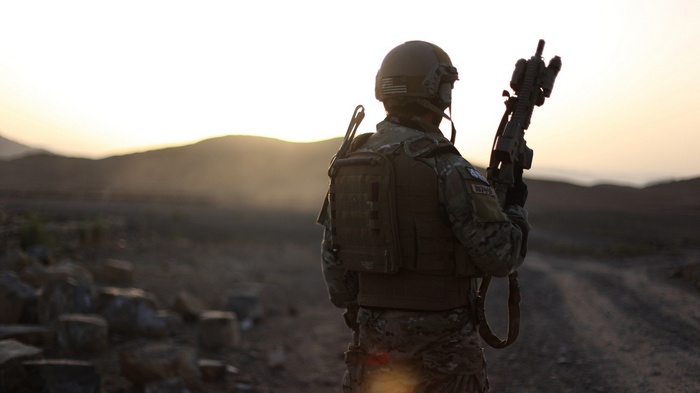 Soldier with AR-15 rifle in desert at sunset