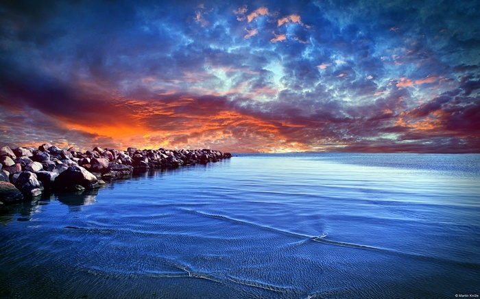 Dramatic sunset over the sea with a rocky shore