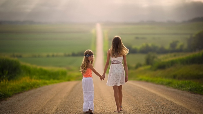 Two girls holding hands on a road in Nebraska