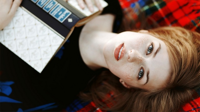 Redhead woman with freckles holding a book