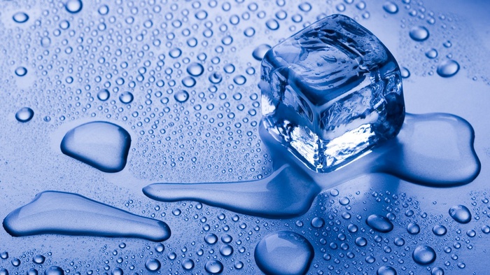 Melting ice cube with water drops on a blue surface