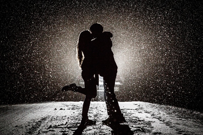 Couple kissing in the snow with backlighting