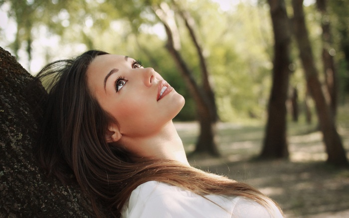 Lorena Garcia leans against a tree looking up