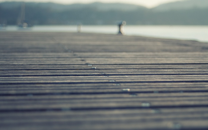 Wooden pier extending over water with hills in background