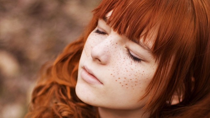 Woman with red hair and freckles with closed eyes