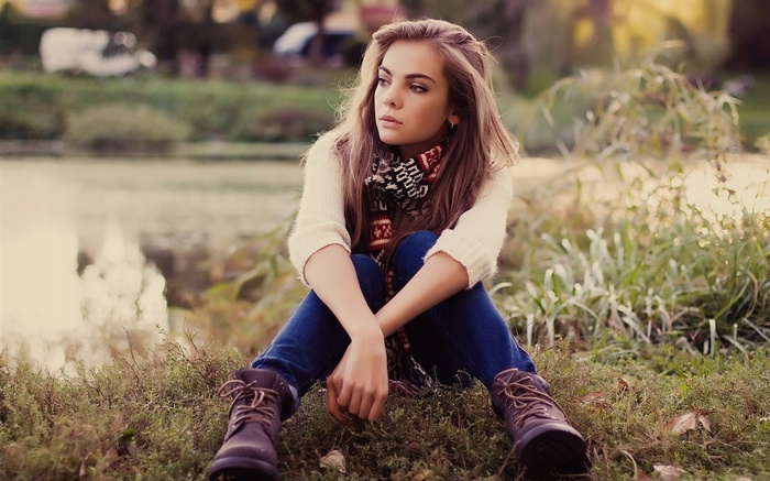 Woman with auburn hair wearing a scarf and jeans outdoors