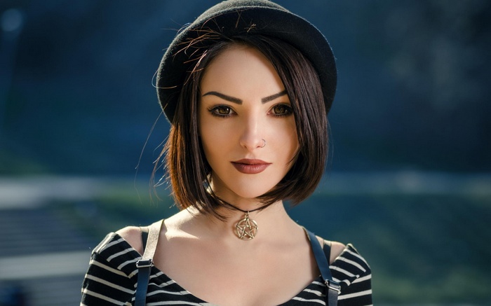 Woman with short hair wearing a hat and a pentagram necklace
