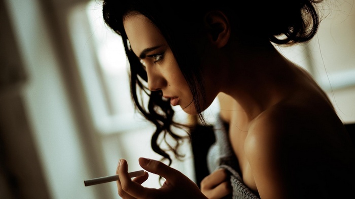 Woman with dark hair smoking a cigarette