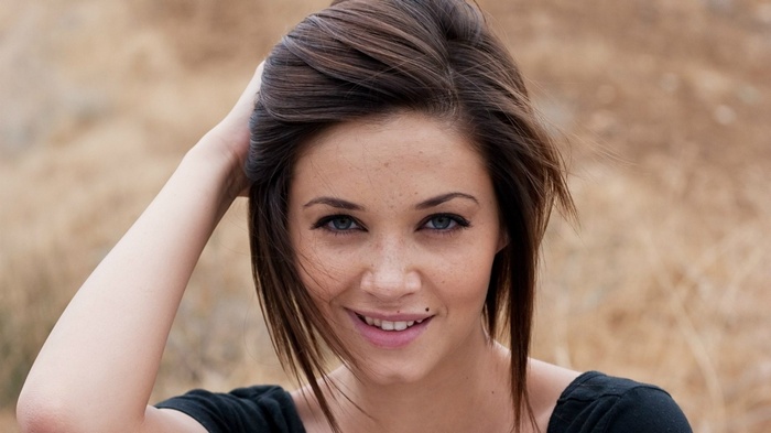 Woman with dark hair smiling outdoors