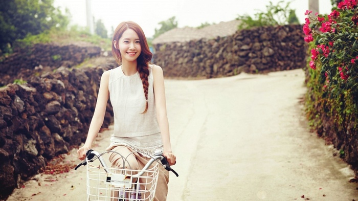 Asian woman riding a bicycle on a rural road