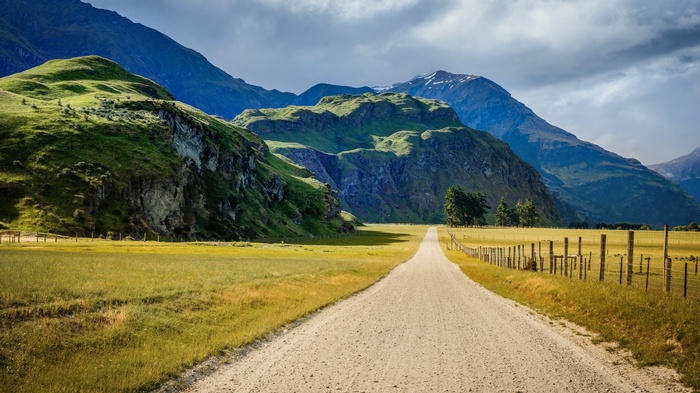 Dirt road through a green valley with mountains