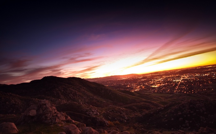 Cityscape at dusk with mountains and sunset sky