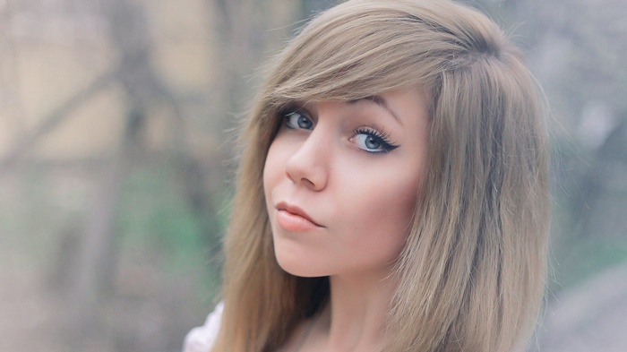 Woman with blonde hair and makeup looking at viewer
