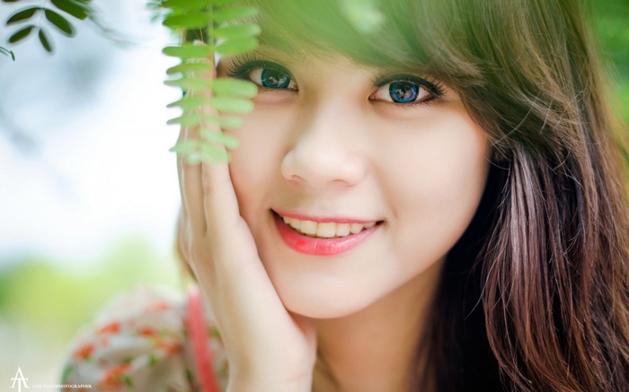 Young woman with blue eyes and green leaves