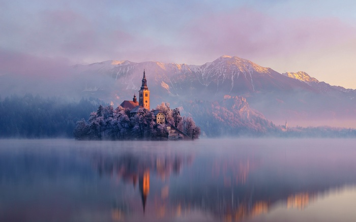 Lake Bled island church with mountains and mist