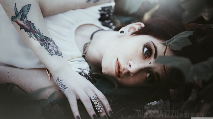 Woman with tattoos lying in leaves