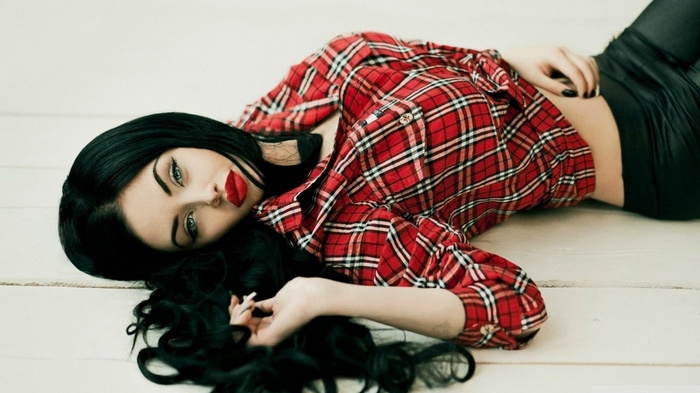 Woman with dark hair and red lipstick lying down