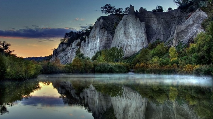 Rock formations reflected in a misty lake at sunset
