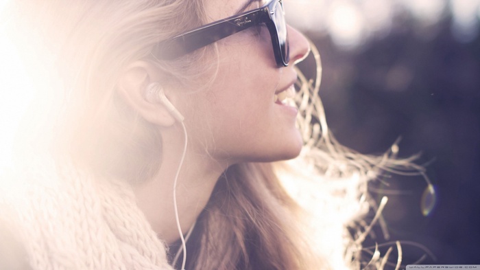 Woman wearing sunglasses and headphones listening to music