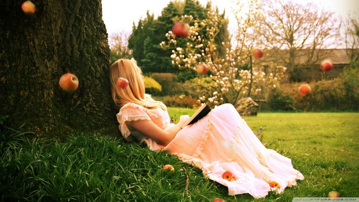 Woman in white dress reading under apple tree
