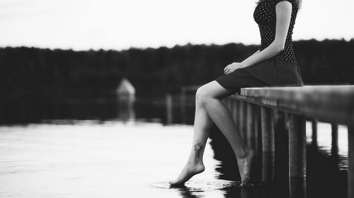 Woman with tattoo sitting on a pier by the water