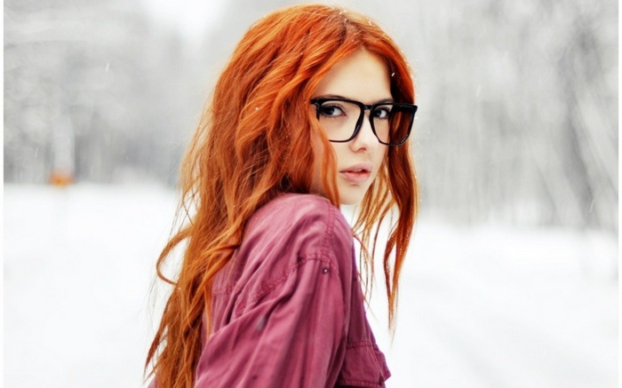 Woman with red hair and glasses in the snow