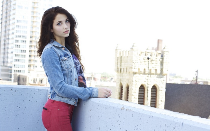 Emily Rudd on a rooftop with buildings in the background