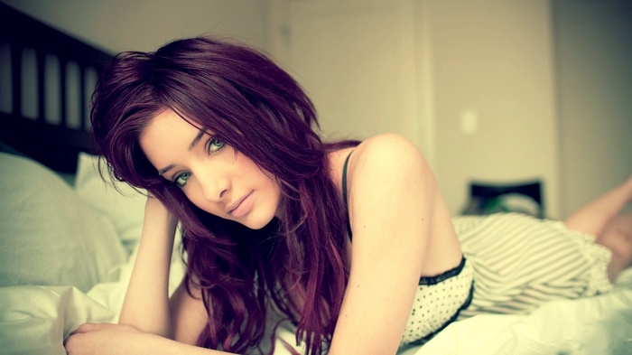 Woman with dyed hair lying on a bed