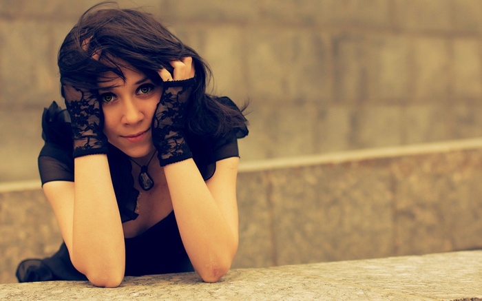 Woman with dark hair and green eyes wearing black lace gloves
