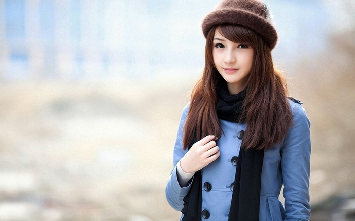 Asian woman with long brown hair wearing a hat and coat
