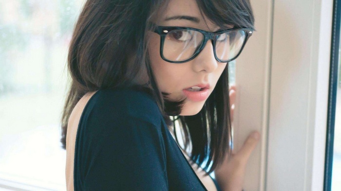 Laura Baduria wearing glasses by a window