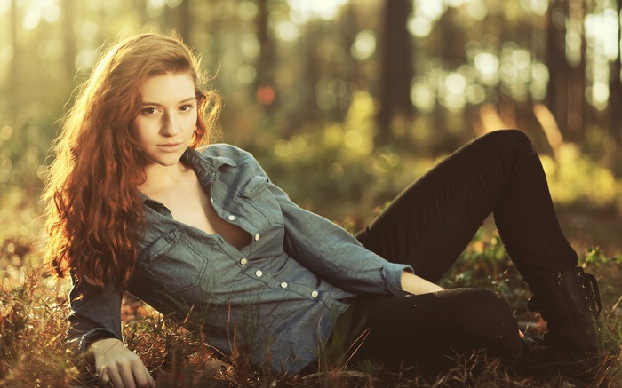 Redhead woman lying in a forest with sunlight