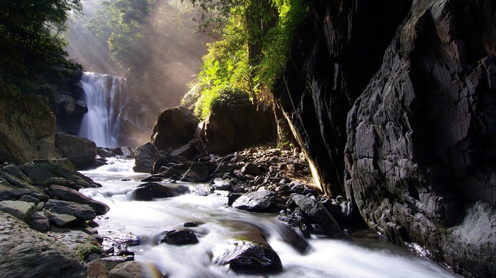 Sun rays over a waterfall and river in a rocky landscape