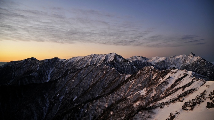 Snow-covered mountains at sunrise with clouds