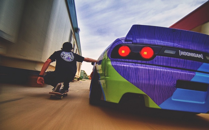 Skateboarder next to a colorful Hoonigan car